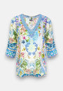 Princess Goes Hollywood präsentiert eine farbenfrohe, locker sitzende Seidentunika mit Dreiviertelärmeln, die mit floral-geometrischen Prints in Blau, Gelb, Rosa und Grün und einem V-Ausschnitt mit dekorativen blauen Mustern für einen Bohème-Touch sorgt.