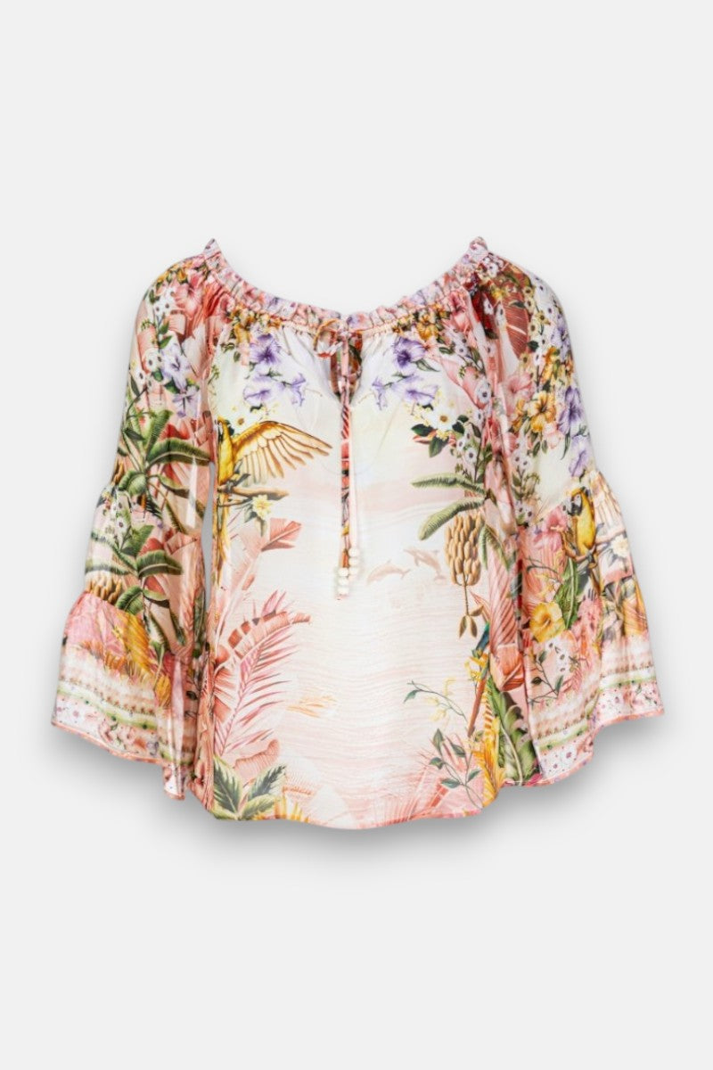 Die Princess Goes Hollywood Carmenbluse Seide ist ein lockeres, schulterfreies Oberteil mit ausgestellten Volantärmeln und einem farbenfrohen, tropischen Druck aus bunten Vögeln, Blumen und üppigem grünen Laub auf hellrosa. Es hat einen gerafften Ausschnitt mit Bindeband in der Mitte.