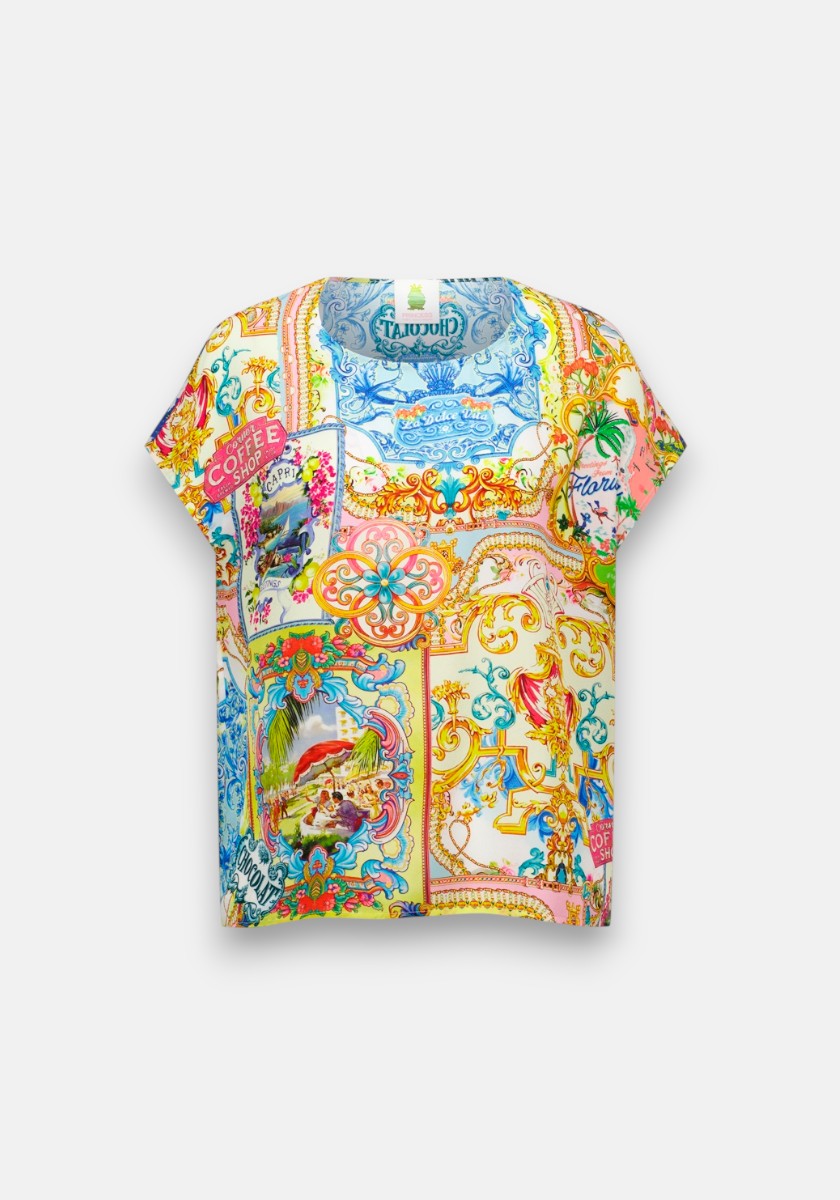 Ein locker sitzendes, kurzärmeliges Blusenshirt von Princess Goes Hollywood mit einem lebendigen Dolce-Vita-Print mit verzierten Rahmen, Palmen, tropischen Motiven und Vintage-Postkartengrafiken auf weißem Hintergrund für einen eklektischen, verspielten Look.