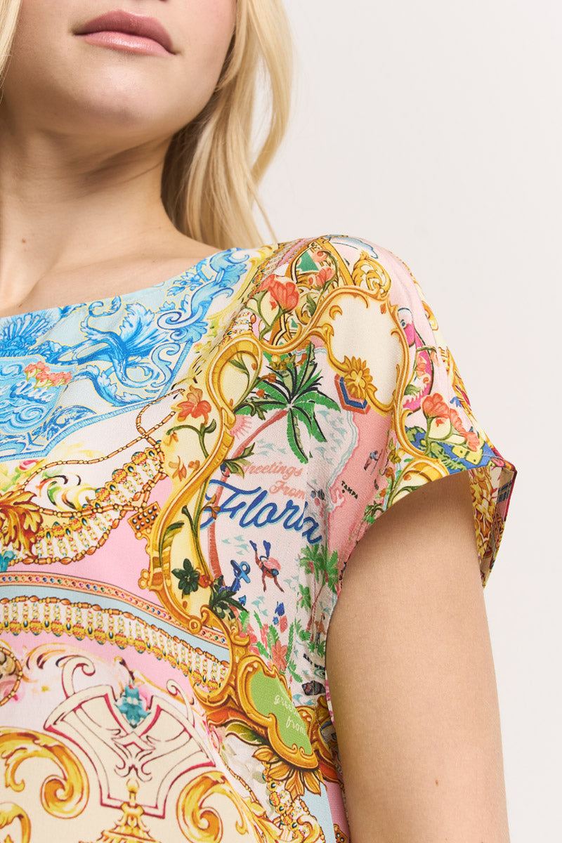 Eine Frau mit heller Haut und langem blondem Haar modelliert eine Princess Goes Hollywood Damen Shirt-Bluse mit einem verzierten Dolce Vita Print in Gelb, Grün, Pink und Blau mit dem Schriftzug "Florida" und kleinen Palmen. Nur ihr unteres Gesicht und ihr Oberkörper sind zu sehen.