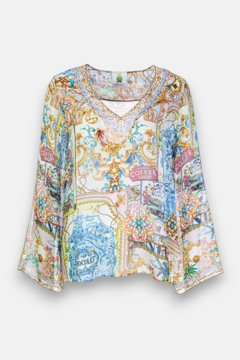 Eine farbenfrohe Princess Goes Hollywood Seidenbluse mit langen Ärmeln und V-Ausschnitt, mit einem Dolce Vita-Print aus Blumen, Ketten, Schnörkeln und grafischen Elementen wie "COFFEE SHOP" und "CHOCOLAT" auf hellem Grund.
