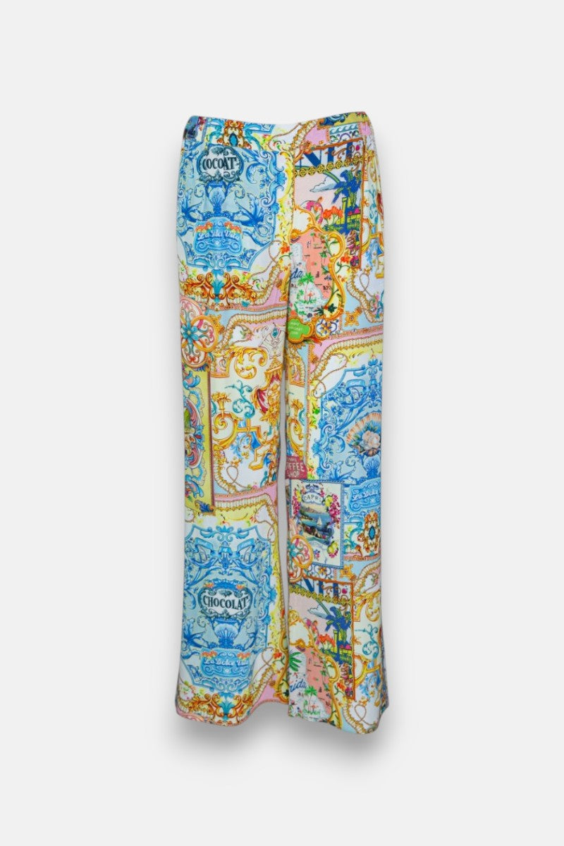 Die Seidenhose mit weitem Bein von Princess Goes Hollywood zeigt einen farbenfrohen Dolce Vita-Druck mit blauen, gelben, orangefarbenen und rosafarbenen barocken Verzierungen, Blumen und "CHOCOLAT"-Motiven auf weißem Grund.