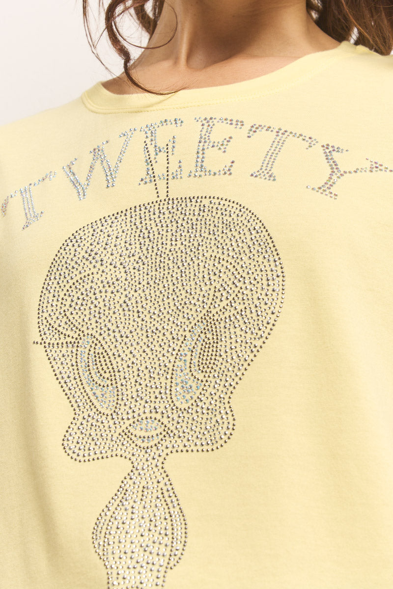 Nahaufnahme einer Person in einem hellgelben Princess Goes Hollywood Baumwolle Tweety T-Shirt mit funkelnden Strass-Akzenten, die das Gesicht von Tweety Bird bilden. Der Schriftzug "TWEETY" ist oben in passenden Strasssteinen aufgedruckt. Nur das untere Gesicht und der Hals sind sichtbar.