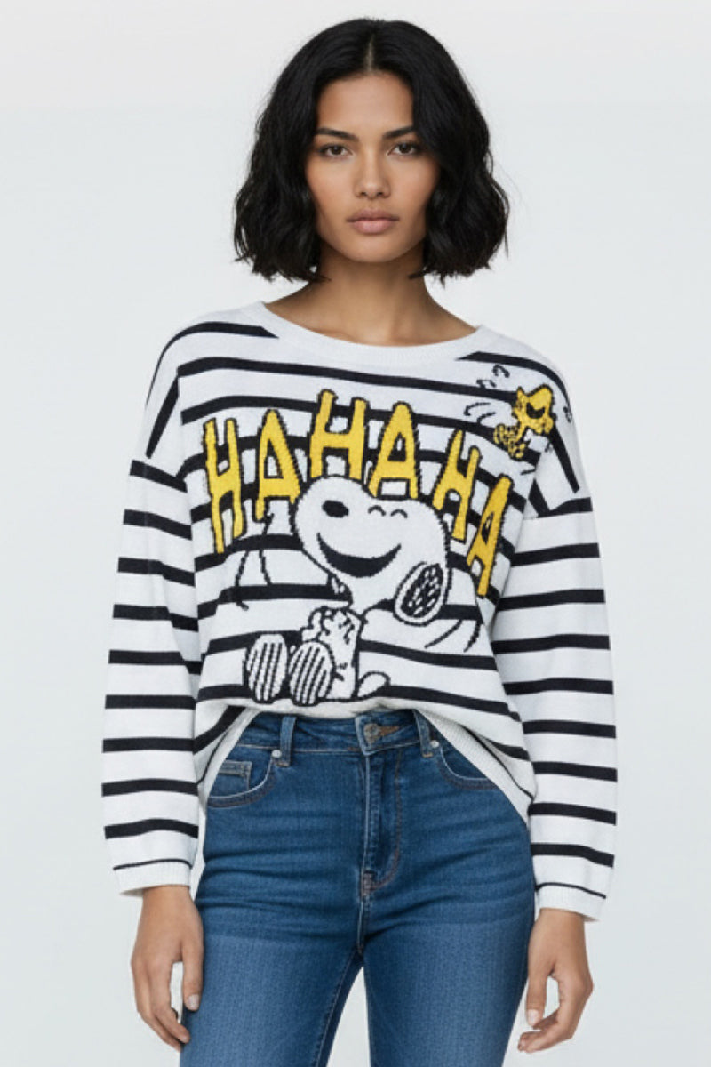 Eine Frau mit schulterlangen dunklen Haaren trägt einen gestreiften Pullover von Princess Goes Hollywood mit Snoopy-Motiv, gelbem "HAHAHA" und Woodstock daneben, gepaart mit blauen Jeans, vor einem hellen Hintergrund.