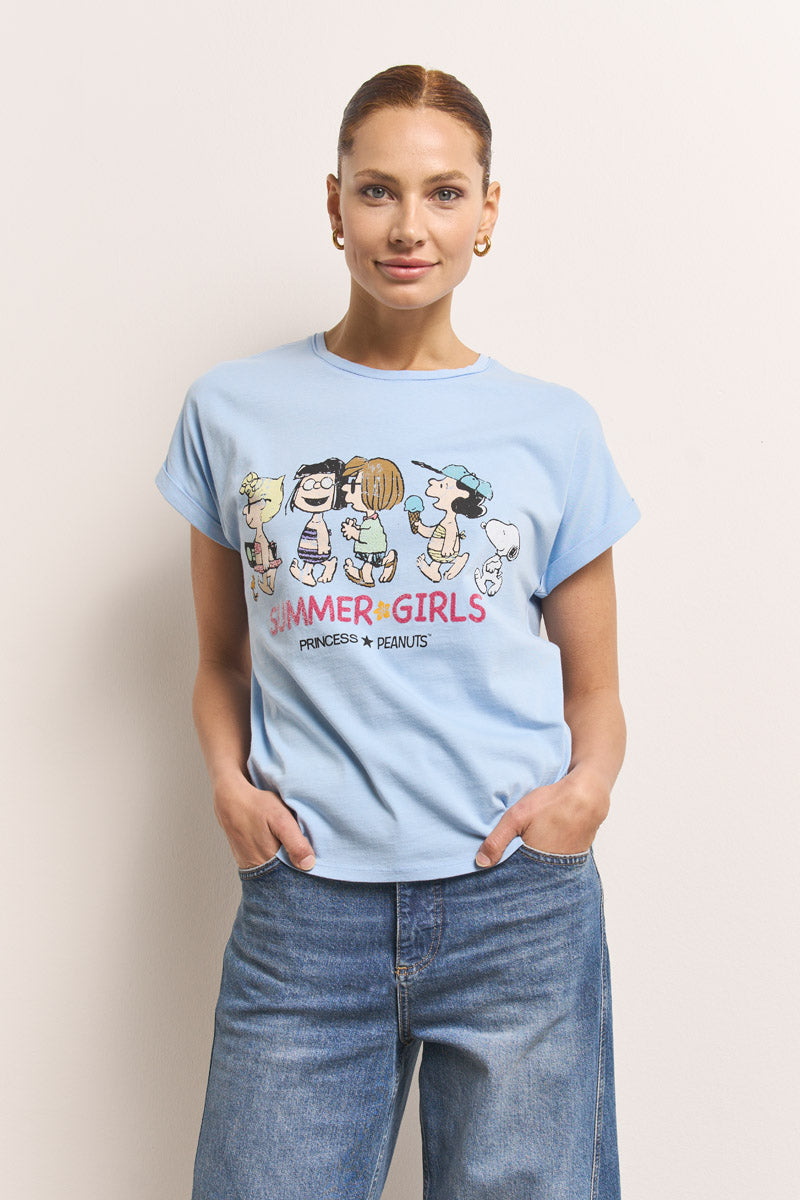 Eine Frau mit braunen Haaren in einem Pferdeschwanz trägt goldene Ohrringe, blaue Jeans und ein hellblaues Princess Goes Hollywood Baumwolle T-Shirt mit einem Peanuts-Aufdruck und dem Text "SUMMER GIRLS PRINCESS * PEANUTS". Sie steht vor einem hellen Hintergrund, die Hände in den Taschen.