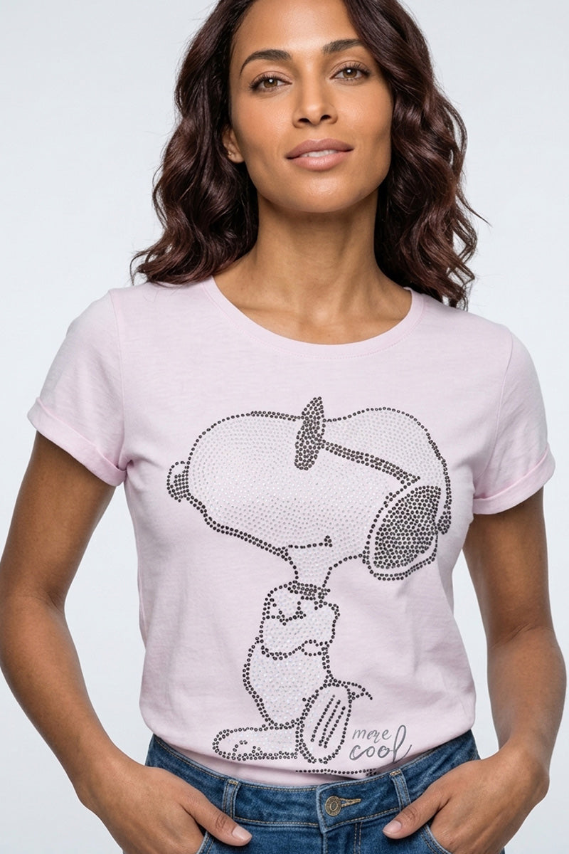 Eine selbstbewusste Frau mit gewellten braunen Haaren trägt ein hellrosa Princess Goes Hollywood T-Shirt aus Baumwolle mit einem Snoopy-Print mit Strassdeko um Snoopy und Woodstock, plus "mee cool" am unteren Rand, mit den Händen in der Taille stehend.
