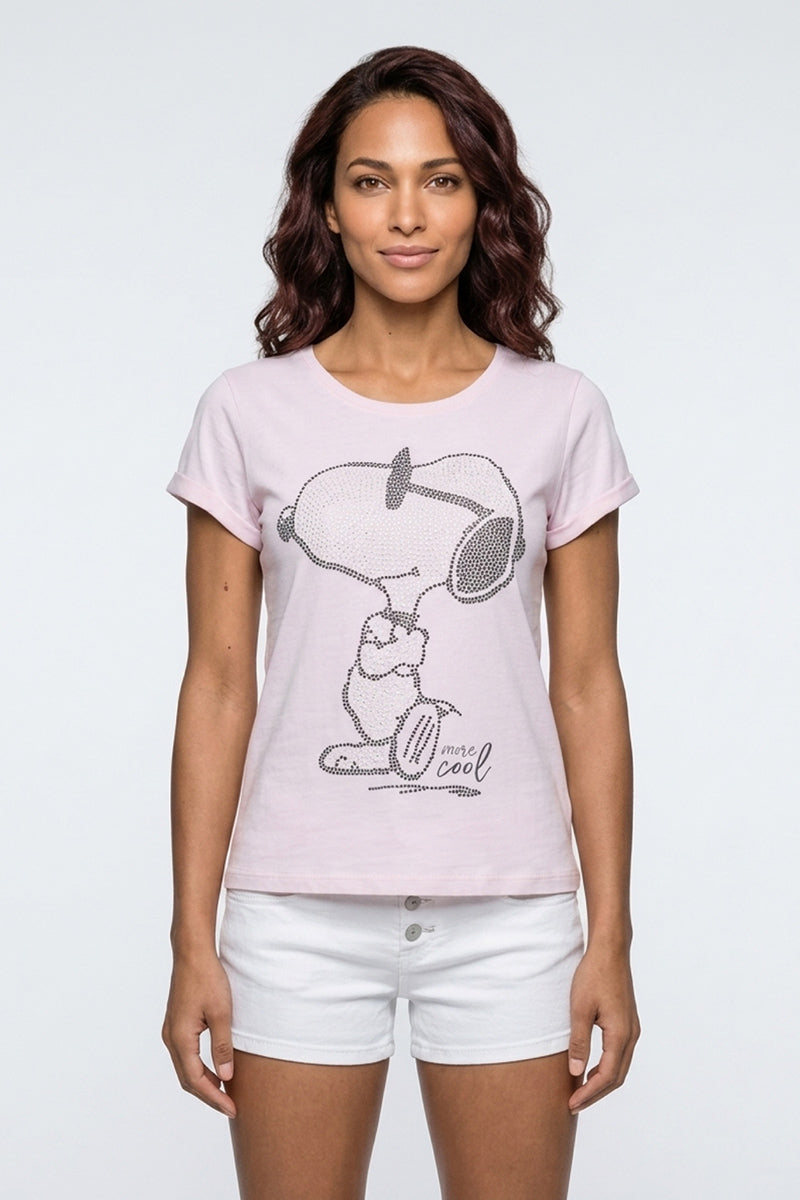 Eine Frau mit gewelltem dunklem Haar trägt ein hellrosa Princess Goes Hollywood-Baumwoll-T-Shirt mit Snoopy, Woodstock und dem Text "1 more cool". Sie steht mit dem Gesicht nach vorne in weißen Shorts vor einem schlichten hellgrauen Hintergrund.