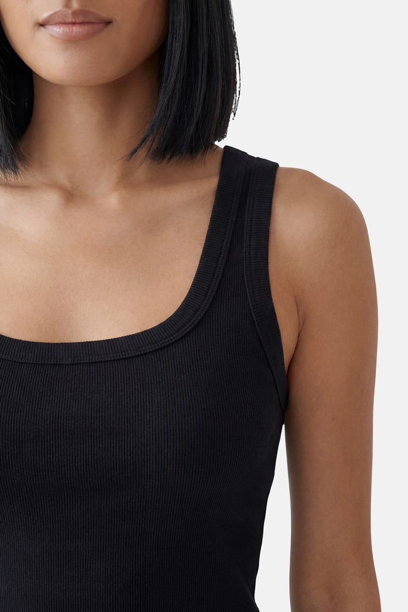 Eine Frau mit glattem schwarzem Haar und mittlerem Teint trägt ein eng anliegendes, geripptes „Princess Goes Hollywood Basic Top“ aus Baumwolle. Das Bild, das bis zu ihren Lippen und zur Mitte ihres Oberkörpers beschnitten ist, hebt den Rundhalsausschnitt und die Struktur des Oberteils vor einem schlichten weißen Hintergrund hervor.