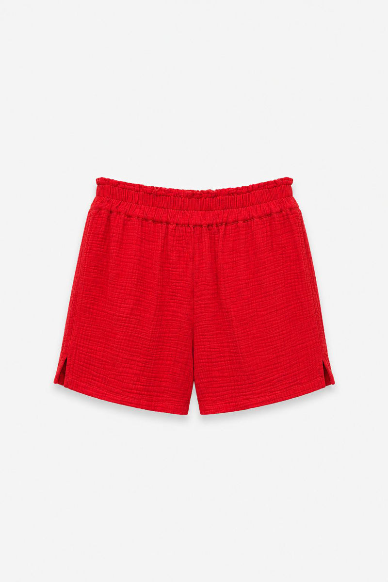 Diese limitierte Auflage der Baumwollmusselin-Shorts von Princess Goes Hollywood in leuchtendem Rot besticht durch einen strukturierten, gekräuselten Stoff, einen elastischen Bund und kleine Seitenschlitze. Das Modell „Kurze Hose Damen“ wird vor einem schlichten weißen Hintergrund präsentiert.