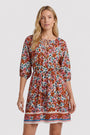 Eine Frau blickt nach vorne in einem Princess Goes Hollywood Limited Edition Kleid mit V-Ausschnitt, geraffter Taille, Dreiviertel-Ärmeln, Schlüssellochausschnitt und einem bunten Blumenmuster in Rosa, Blau und Orange mit gestreiftem Saumbesatz.