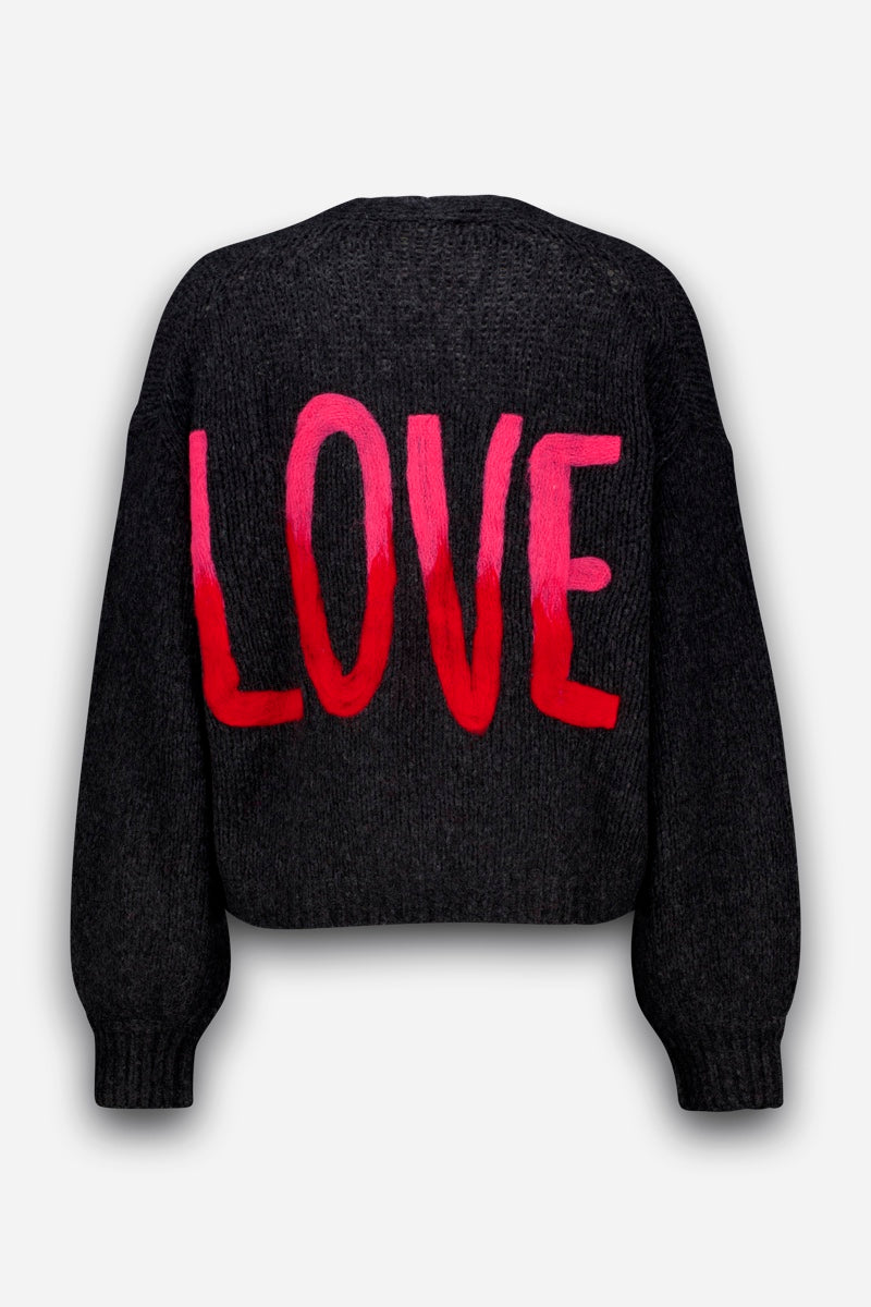 Eine dunkelgraue, handgestrickte Merino-Alpaka-Strickjacke, auf deren Rücken das Wort „LOVE“ in großen, markanten roten Buchstaben aufgedruckt ist. Die langen Ärmel und der schlichte weiße Hintergrund lassen den leuchtend roten Schriftzug wunderschön zur Geltung kommen, während dezente Herz-Intarsien-Details diesem auffälligen Kleidungsstück eine charmante Note verleihen.