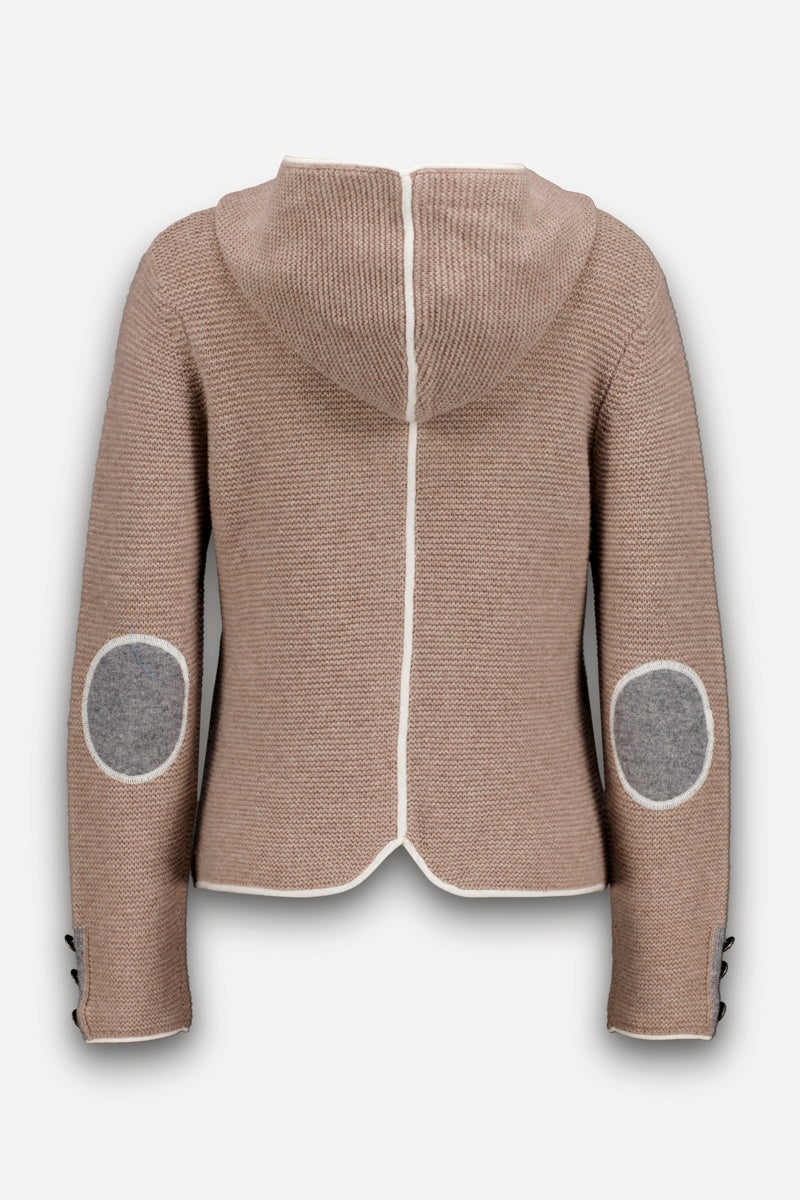 Eine beigefarbene Kapuzenjacke aus einem Woll-Kaschmir-Mix wird von hinten gezeigt. Sie verfügt über eine weiße Paspelierung in der Mitte und entlang der Kapuzennaht, graue ovale Ellbogenpatches sowie schwarze Knöpfe an den Ärmelbündchen. Der Saum ist hinten leicht geschwungen, was dieser kuscheligen Strickjacke einen dezenten Charme im bayerischen Stil verleiht.