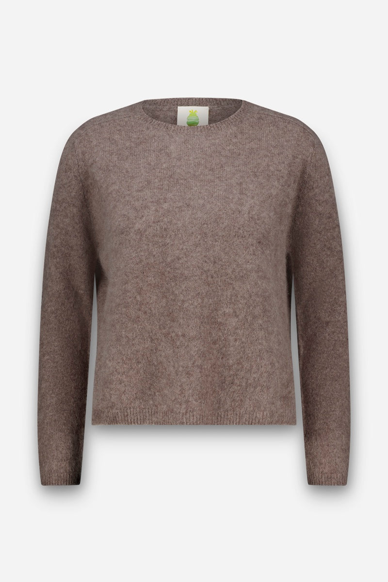 Brauner, langärmeliger, flauschiger Pullover mit klassischem Rundhalsausschnitt, abgebildet vor einem schlichten weißen Hintergrund. Der Stoff wirkt weich und flauschig, was an gebürstete Wolle erinnert, mit gerippten Bündchen und Saum. Keine sichtbaren Muster oder Motive. Im Kragenbereich ist ein weißes Nackenetikett mit grünem Logo zu sehen.