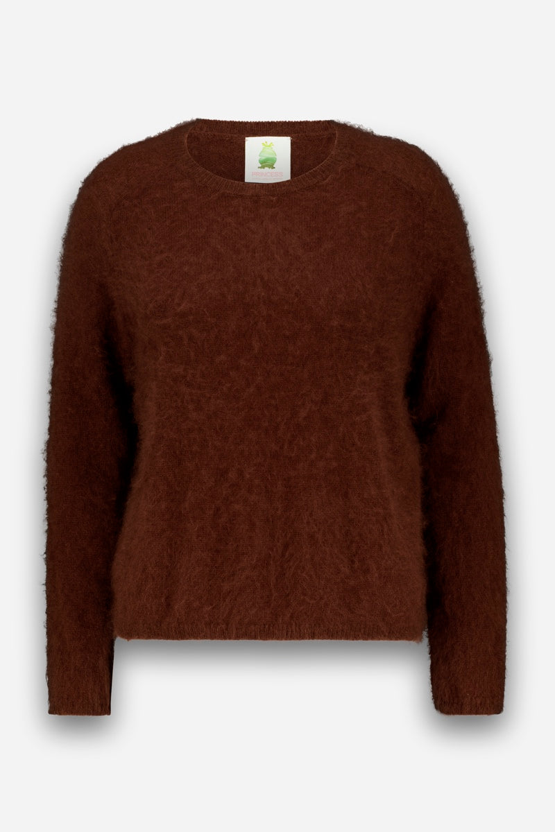 Ein brauner, langärmeliger, flauschiger Strickpullover mit Rundhalsausschnitt. Dieser flauschige Pullover aus weicher, gebürsteter Wolle ist mit einem weißen Etikett mit einem kleinen grünen Logo am Hals versehen. Der Hintergrund ist schlicht weiß.