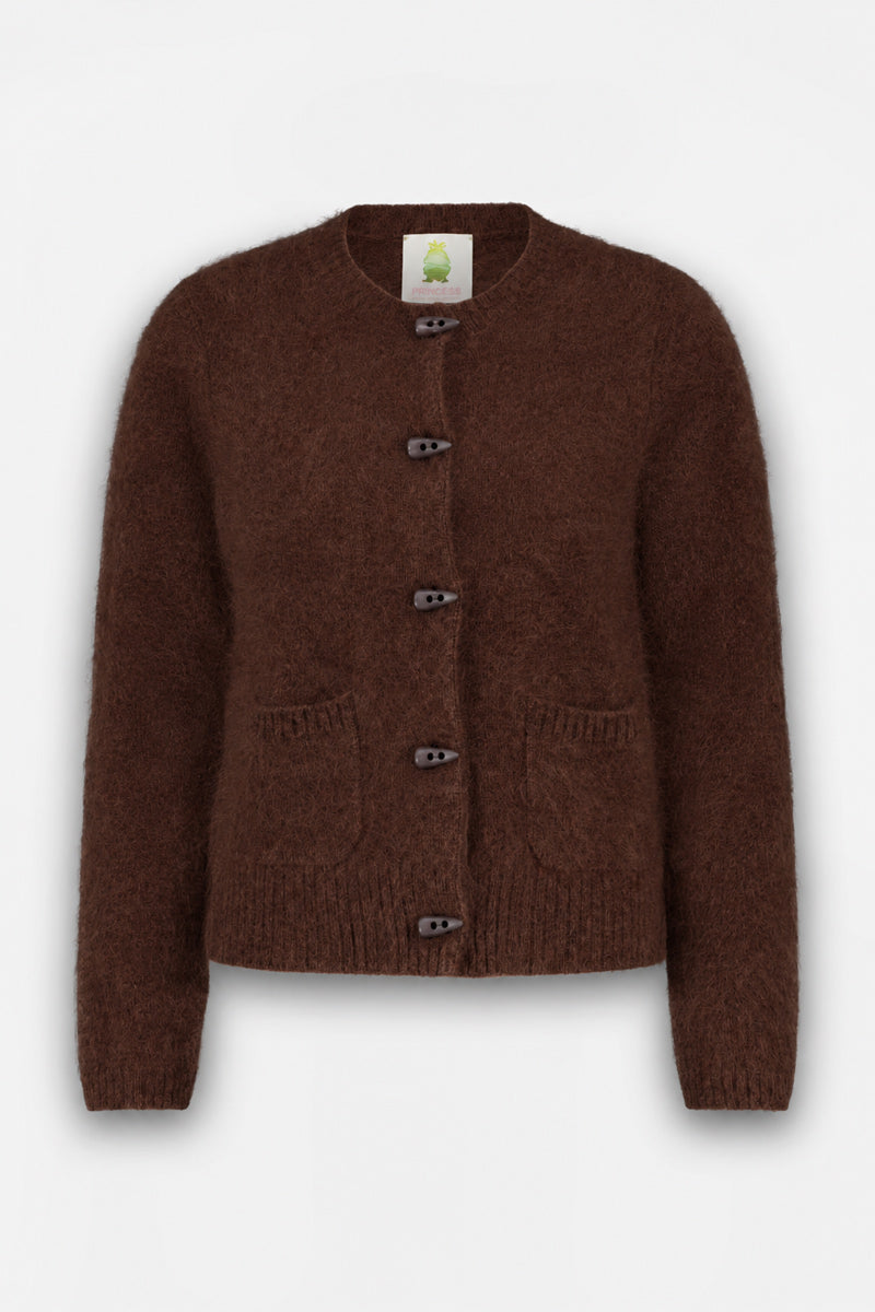 Eine braune, flauschige Strickjacke mit langen Ärmeln, zwei Vordertaschen und vier dunklen Knöpfen in der Mitte. Diese flauschige Strickjacke aus gebürsteter Wolle mit klassischem Rundhalsausschnitt hat eine bequeme, lockere Passform. Das Etikett auf der Innenseite zeigt die Illustration eines grünen Baums auf weißem Hintergrund.