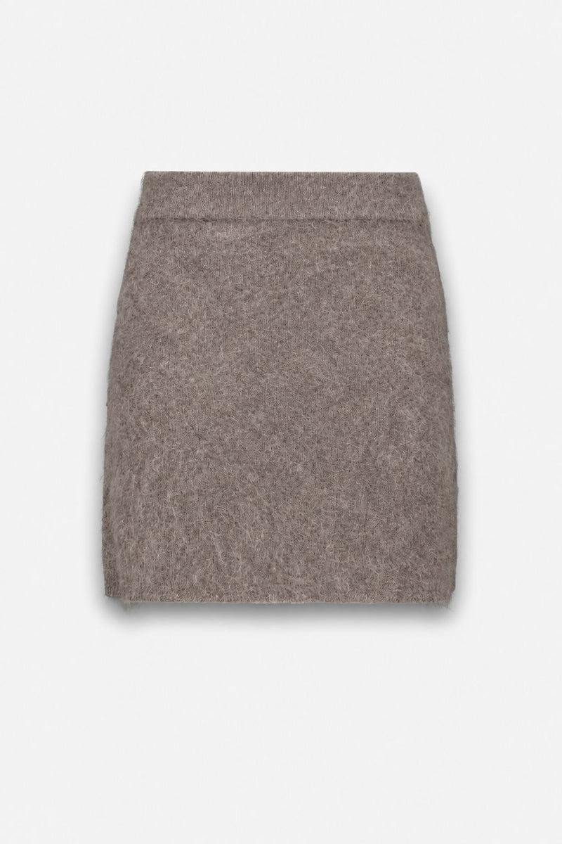 Ein taupefarbener, flauschiger Minirock wird vor einem schlichten weißen Hintergrund präsentiert. Der Rock hat einen geraden Schnitt mit einem schlichten, elastischen Bund und keine sichtbaren Reißverschlüsse oder Knöpfe, was sein minimalistisches Design unterstreicht.