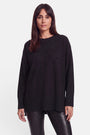 Eine Frau mit glattem, dunkelbraunem Haar, die einen locker sitzenden schwarzen Pullover aus Merino-Kaschmir mit dezenter Strassverzierung und eine schwarze Lederhose trägt, steht mit dem Blick nach vorne vor einem schlichten weißen Hintergrund.