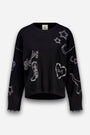Ein schwarzer Pullover aus Merino-Kaschmir mit weißen Western-Stickereien: „Howdy“-Schriftzug, ein Cowboystiefel, Sterne, ein Herz mit der Aufschrift „LOVE“ und Stacheldraht, das Wort „LOVE“ sowie ein Longhorn-Kopf. Der Pullover hat einen gerippten Saum und Ärmelbündchen sowie eine leicht verkürzte, kastenförmige Passform.