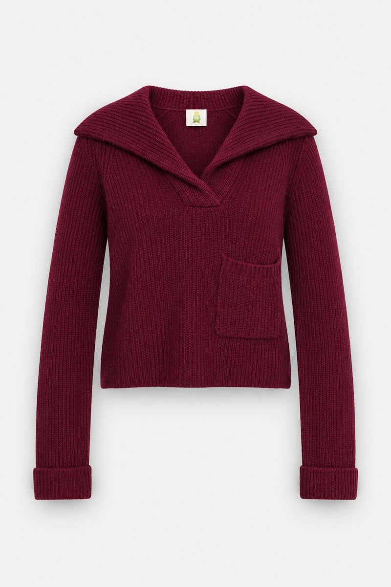 Ein langärmeliger, tief burgunderroter Strickpullover aus einer weichen Wolle-Kaschmir-Mischung mit einem breiten, offenen V-Ausschnitt, einer Brusttasche vorne und umgeschlagenen Ärmelbündchen. Der Pullover hat eine verkürzte, lockere Passform ohne sichtbare Verschlüsse und wird vor einem schlichten weißen Hintergrund präsentiert.