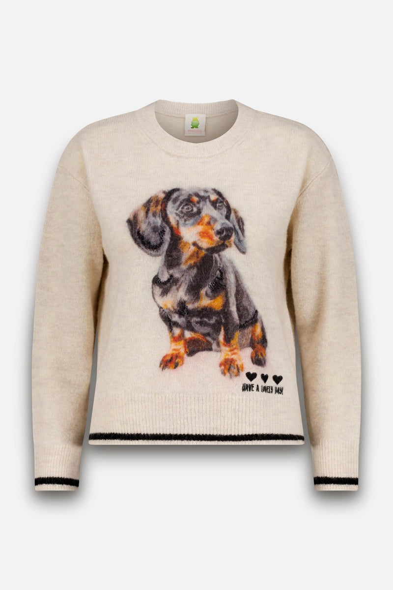 Ein cremefarbener Strickpullover für Damen mit klassischem Rundhalsausschnitt, verziert mit einem realistischen Motiv eines schwarz-braunen Dackels auf der Vorderseite. Am Saum sorgen drei kleine schwarze Herzen und der Schriftzug „HAVE A LOVELY DAY“ für eine charmante Note. Schwarze Paspeln an den Ärmelbündchen und am Saum machen diesen Pullover aus Alpaka-Wolle sowohl kuschelig als auch stilvoll.