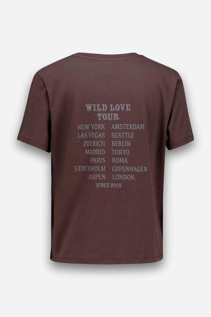 Ein braunes T-Shirt aus Baumwolle mit dem Aufdruck „WILD LOVE TOUR“ auf der Rückseite in verblasstem Weiß, ergänzt durch eine Auflistung bedeutender Städte wie New York, Amsterdam, Las Vegas, Berlin, Tokio und Paris. Unten steht der Schriftzug „SINCE 2005“ – perfekt für Fans der Wild Love Tour und alle, die einzigartige, von der Tour inspirierte Designs schätzen.