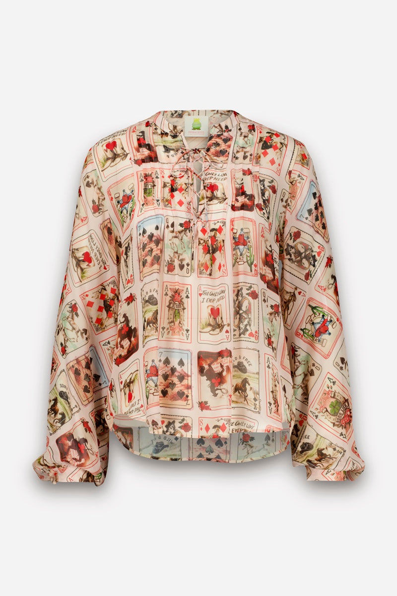 Eine langärmelige, hellrosa, fließende Bluse besticht durch ihre lockere Passform und ein Muster aus farbenfrohen Western-Karten-Prints. Die Bluse hat einen Rundhalsausschnitt mit Bindeband und dezenten Falten, was ihr einen fließenden, lässigen Look verleiht.