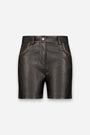 Vorderansicht von schwarzen veganen Ledershorts mit goldener Nietenverzierung entlang der geschwungenen Vordertaschen und Seitennähte, einem Hosenschlitz vorne mit goldenem Knopfverschluss sowie Gürtelschlaufen. Die Shorts zeichnen sich durch eine glatte Textur und eine taillierte Passform vor einem schlichten weißen Hintergrund aus.