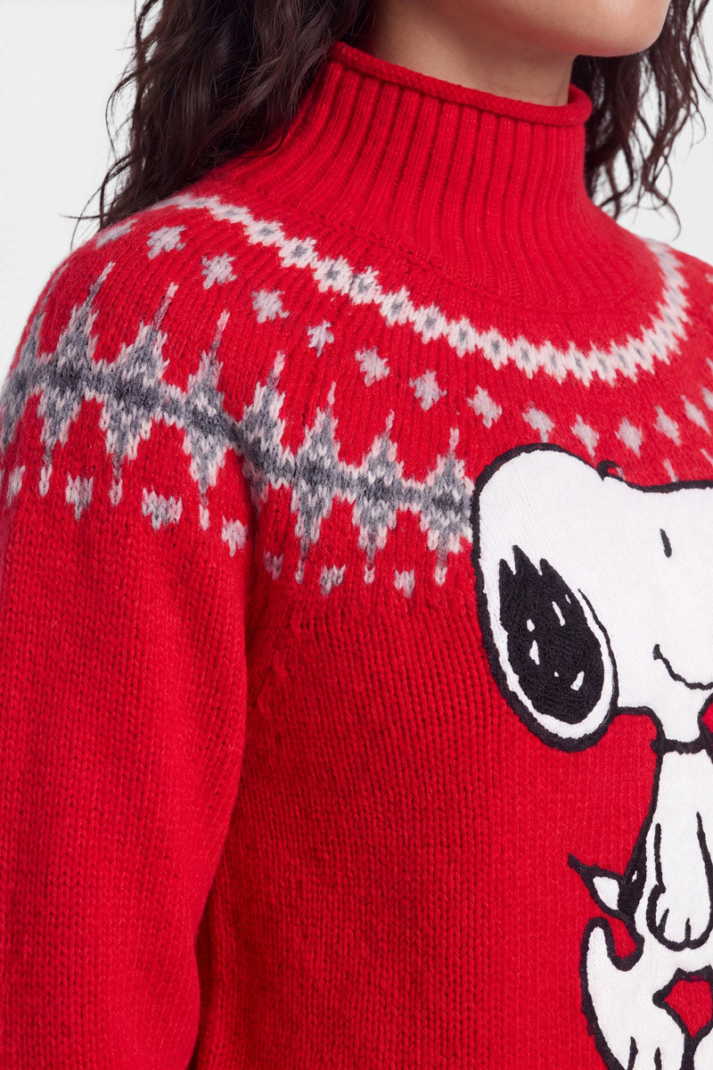 Eine Person trägt einen roten Strickpullover mit geripptem Rollkragen, der über den Schultern ein weiß-graues geometrisches Muster im norwegischen Stil und auf der Brust einen großen Snoopy-Aufdruck aus der Serie „Peanuts“ aufweist. Zu sehen sind nur der untere Teil des Gesichts und der obere Oberkörper.