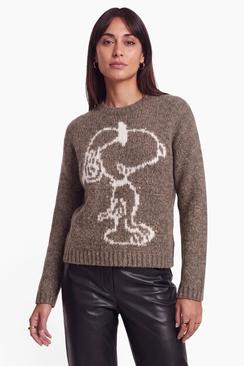 Eine Frau trägt einen braunen Pullover aus einer Mohair-Mischung, auf dessen Vorderseite ein großes weißes Snoopy-Intarsienmotiv zu sehen ist.