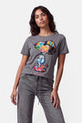 Eine Frau mit welligem, dunklem Haar trägt ein graues Snoopy-T-Shirt aus 100 % Baumwolle mit einem farbenfrohen Pop-Art-Print und dem Schriftzug „NEW YORK“ in kräftiger Schrift am Saum. Dazu trägt sie eine graue Jeans und steht vor einem schlichten weißen Hintergrund, während sie selbstbewusst in die Kamera blickt.