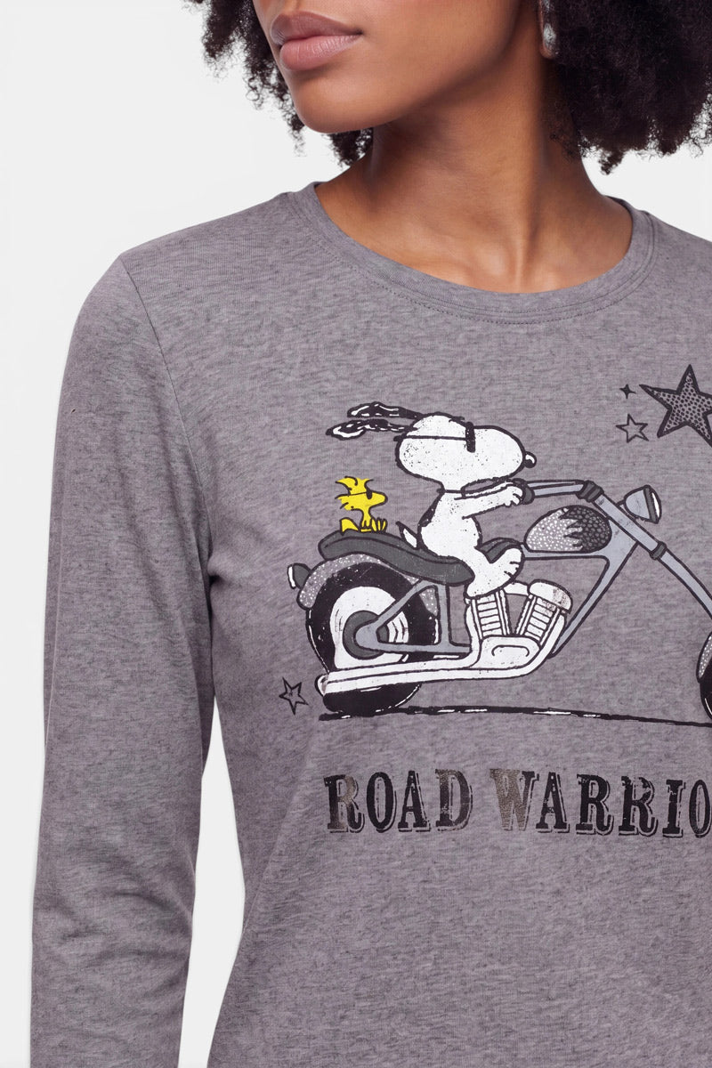 Eine Frau trägt ein graues Langarmshirt aus Baumwolle mit einem Snoopy-Aufdruck, auf dem der beliebte Beagle zu sehen ist, wie er auf einem Motorrad fährt, während Woodstock auf dem Soziussitz sitzt. Unterhalb der Abbildung ist der Schriftzug „ROAD WARRIOR“ aufgedruckt. Zu sehen sind nur die untere Hälfte ihres Gesichts und ihr Oberkörper.