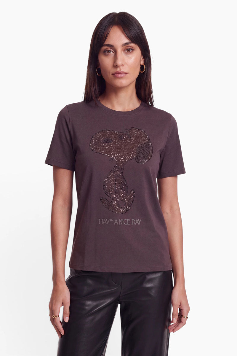 Eine Frau trägt ein braunes Snoopy-T-Shirt aus Baumwolle, auf dem ein mit Strasssteinen verziertes Motiv von Snoopy zu sehen ist, der über dem Schriftzug „HAVE A NICE DAY“ sitzt.