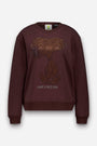 Ein dunkelbraunes Sweatshirt aus Baumwolle mit einem funkelnden, mit Strasssteinen verzierten Snoopy-Aufdruck, auf dem die Figur sitzend abgebildet ist, darunter in kleinen Buchstaben der Schriftzug „HAVE A NICE DAY“.
