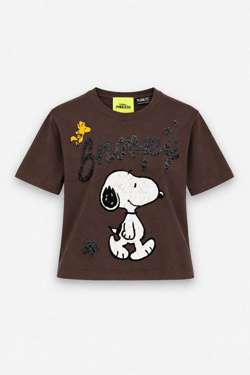 Ein braunes, kurzärmeliges Snoopy-T-Shirt zeigt eine Grafik von Snoopy mit seinem Namen in schwarzer Schreibschrift und einem gelben Woodstock links davon. Das bauchfreie Baumwoll-Top in gerader Passform hat ein Peanuts-Markenlabel an der Innenseite des Halsausschnitts.