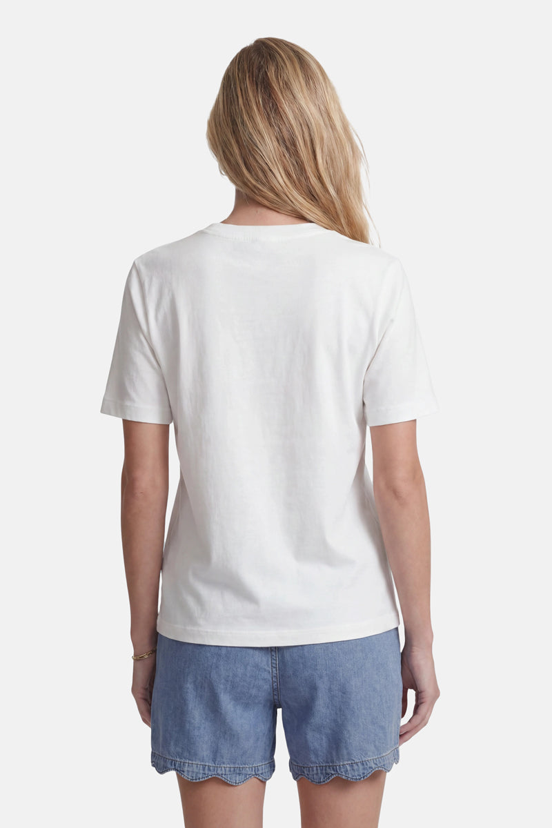 Eine Frau mit langen blonden Haaren steht mit dem Rücken zur Kamera und trägt ein schlichtes weißes Baumwoll-T-Shirt der Marke „Princess Goes Hollywood“ sowie hellblaue Jeansshorts mit gewelltem Saum vor einem schlichten weißen Hintergrund.