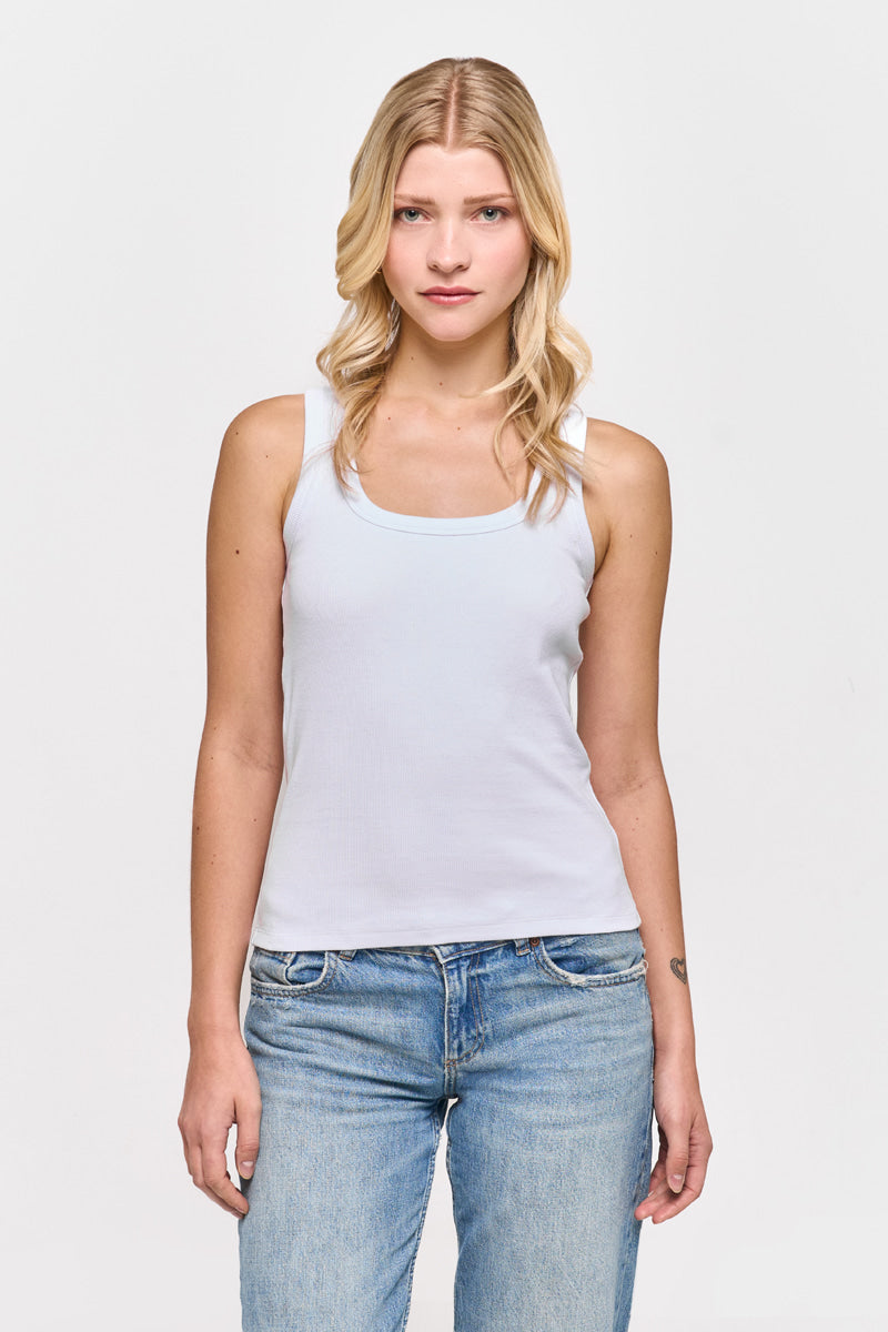 Eine Frau mit langen blonden Haaren trägt ein hellblaues Princess Goes Hollywood Basic Top aus Baumwolle mit Rundhalsausschnitt und blaue Jeans. Sie steht vor einem schlichten weißen Hintergrund und blickt mit neutralem Gesichtsausdruck und entspannten Armen nach vorne.