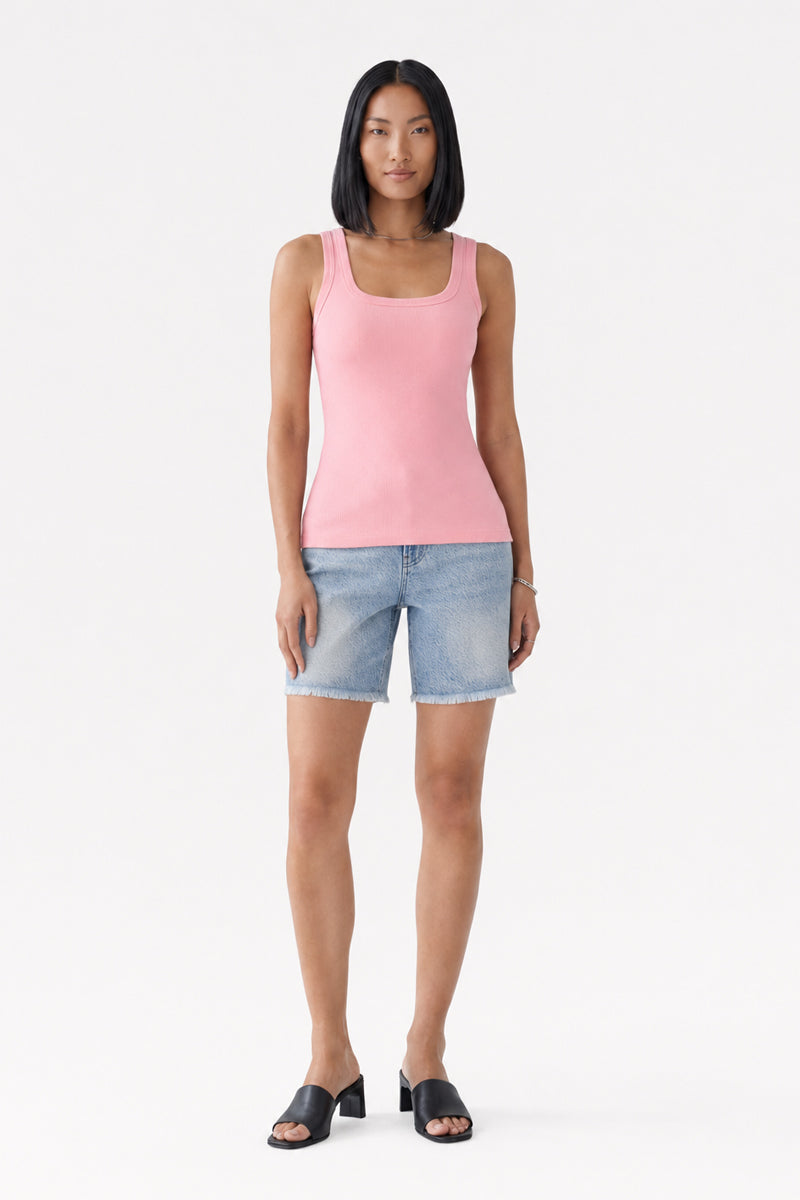 Eine Frau mit glattem schwarzem Haar trägt ein rosa „Princess Goes Hollywood Basic“-Top aus Baumwolle mit Rundhalsausschnitt, hellblaue, knielange Jeansshorts und schwarze Sandalen mit offener Zehenpartie. Sie steht mit dem Blick nach vorne vor einem schlichten weißen Hintergrund, die Arme entspannt an den Seiten.