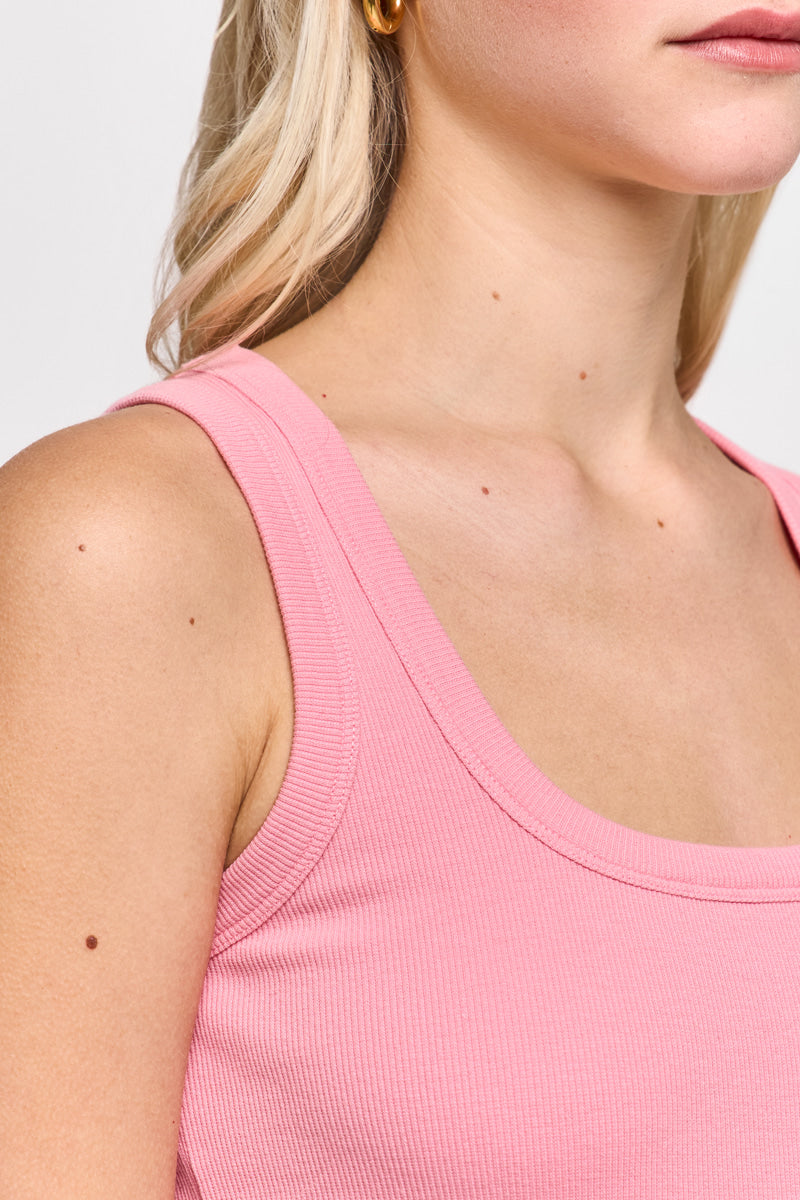 Nahaufnahme einer Person mit heller Haut und langen blonden Haaren, die ein ärmelloses, geripptes Princess Goes Hollywood Basic Top aus Baumwolle mit Rundhalsausschnitt in Pink trägt. Die Aufnahme hebt die Schulter, den Hals, den goldenen Ohrring und die kleinen Muttermale hervor.