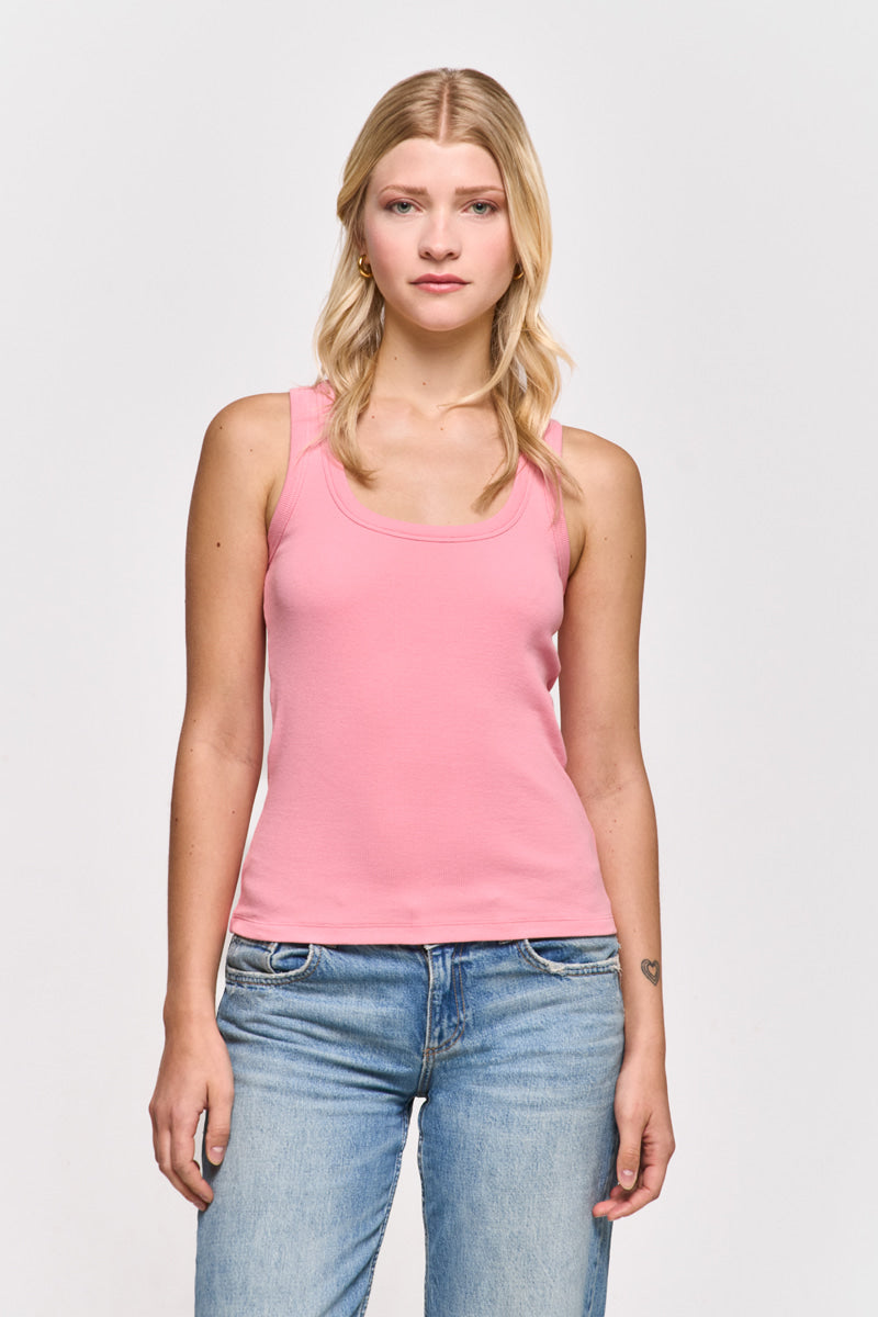 Eine junge Frau mit langen blonden Haaren trägt ein hellrosa Princess Goes Hollywood Basic Top aus Baumwolle mit Rundhalsausschnitt und blaue Jeans. Sie steht vor einem schlichten weißen Hintergrund, hat einen neutralen Gesichtsausdruck und eine kleine Tätowierung auf ihrem linken Unterarm.