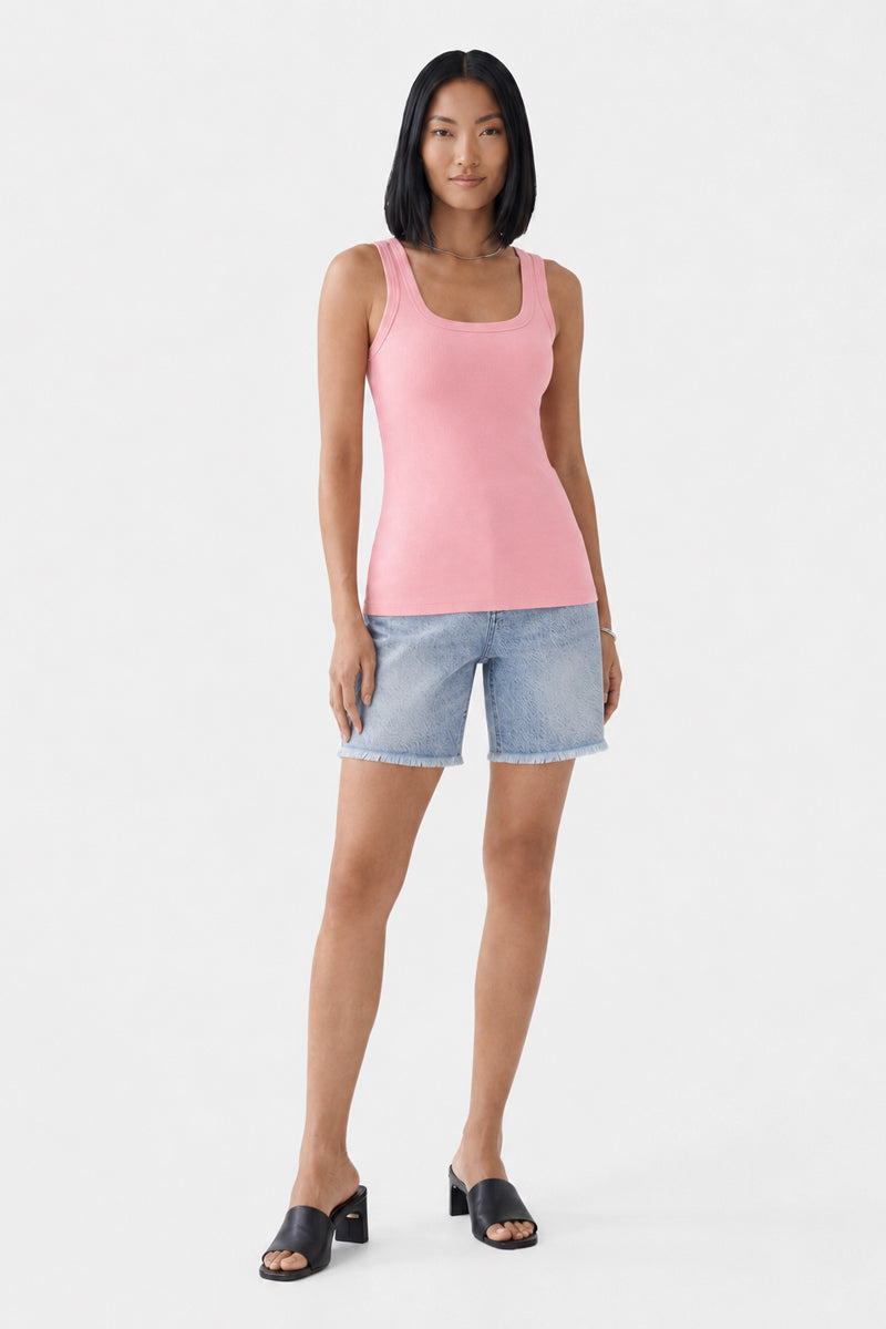 Eine Frau mit glattem schwarzem Haar trägt ein rosa Basic-Top mit Rundhalsausschnitt von Princess Goes Hollywood, hellblaue Jeansshorts und schwarze Pumps mit offener Spitze. Sie steht mit dem Gesicht nach vorne vor einem schlichten weißen Hintergrund, mit neutralem Gesichtsausdruck und den Armen entspannt an den Seiten.