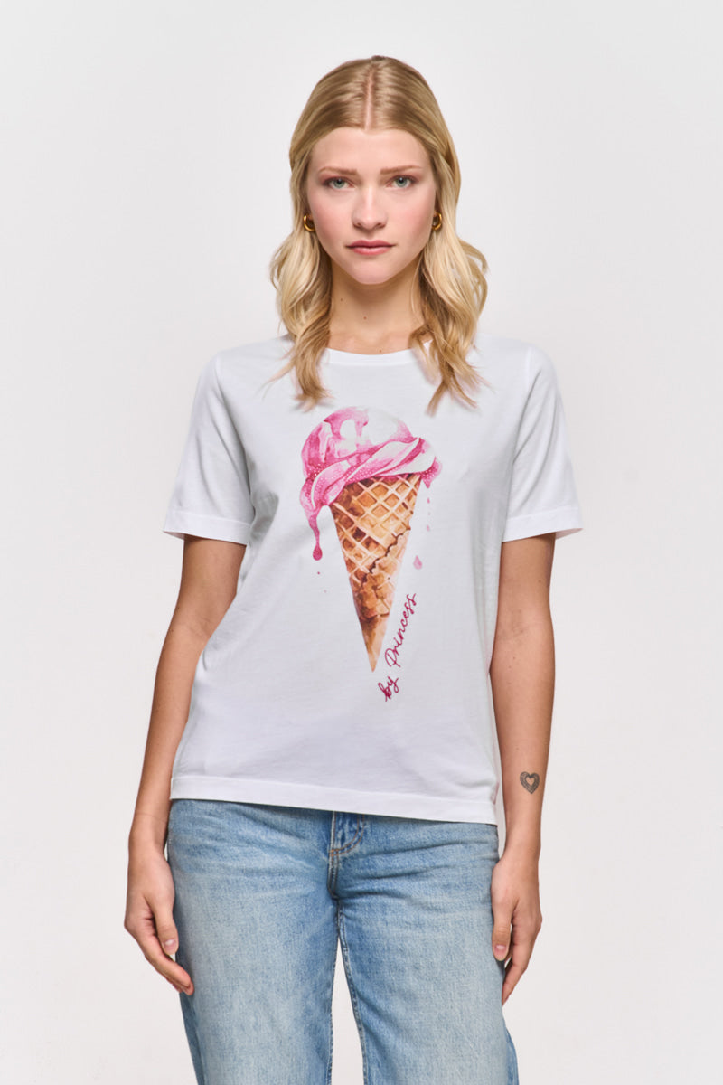 Eine blonde Frau steht mit dem Gesicht nach vorne vor einem schlichten Hintergrund. Sie trägt eine blaue Jeans und ein weißes Baumwoll-T-Shirt von Princess Goes Hollywood mit einem großen rosa Eis-Print. Sie hat einen neutralen Gesichtsausdruck und ein kleines Herz-Tattoo auf ihrem linken Unterarm.