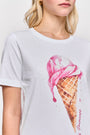 Eine Frau trägt ein weißes Baumwoll-T-Shirt von Princess Goes Hollywood mit großem pinkem Eis-Print und funkelnden Strasssteinen. Sichtbar sind ihre untere Gesichtshälfte, Hals und Oberkörper. Sie hat helle Haut, blonde Haare und goldene Creolen.