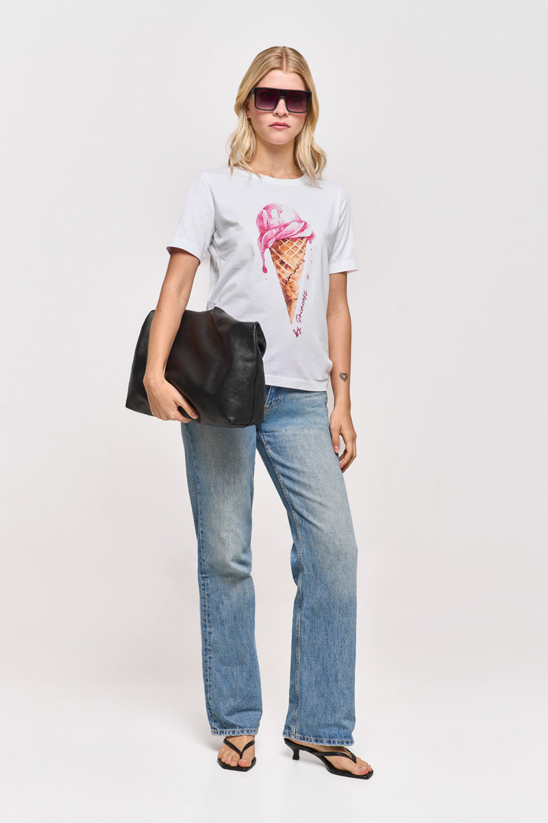 Eine blonde Frau trägt eine rosafarbene Sonnenbrille und ein weißes Princess Goes Hollywood-Baumwoll-T-Shirt mit einem Aufdruck von schmelzendem rosa Eis, hellblaue Jeans, schwarze Sandalen und trägt eine große schwarze Tasche unter dem Arm vor einem schlichten weißen Hintergrund.