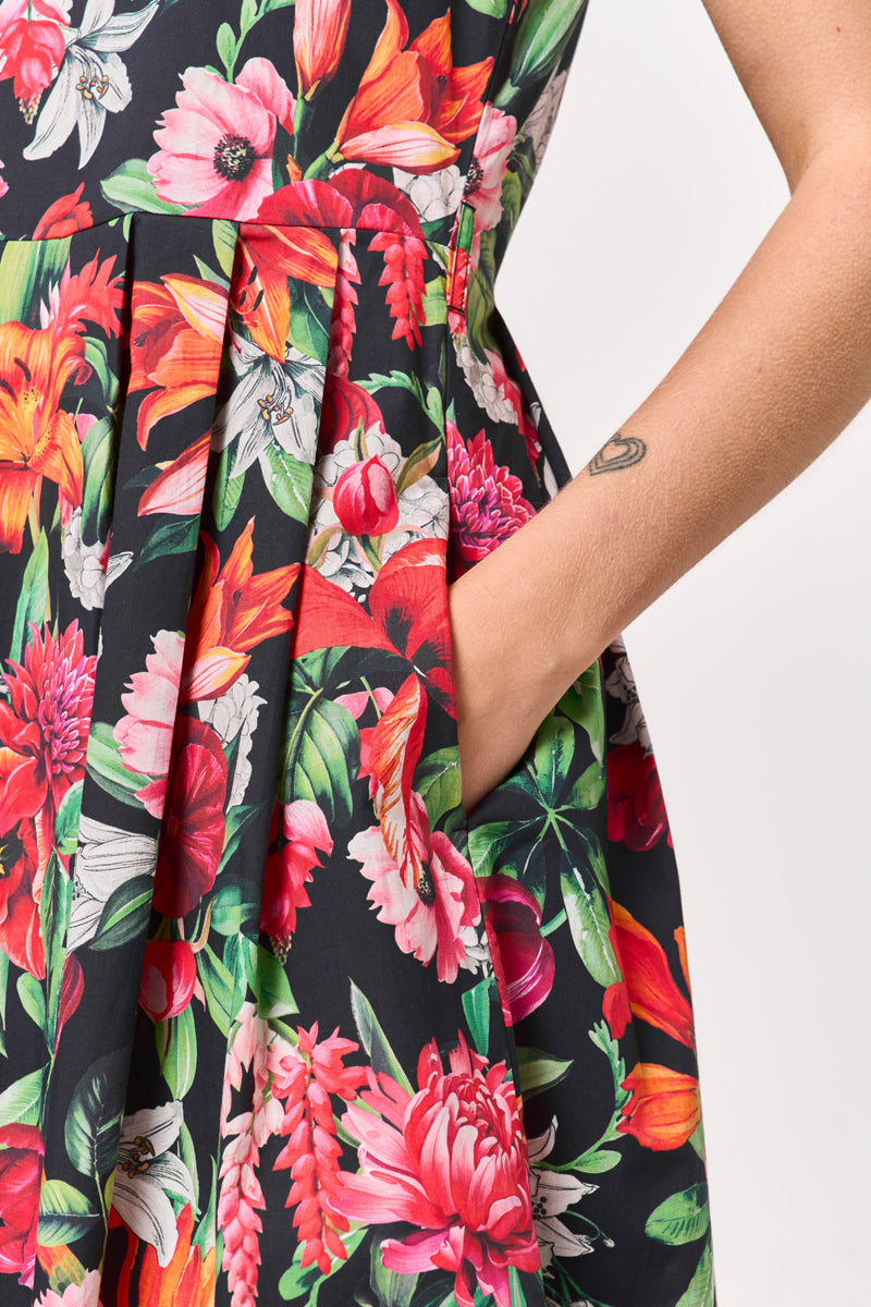 Eine Nahaufnahme einer Person in einem schwarzen Princess Goes Hollywood Baumwolle Minikleid mit einem leuchtend roten, rosa, orangen und grünen Blumenprint. Ihre rechte Hand ruht in der Seitentasche und zeigt einen Teil ihres tätowierten Arms vor einem weißen Hintergrund.