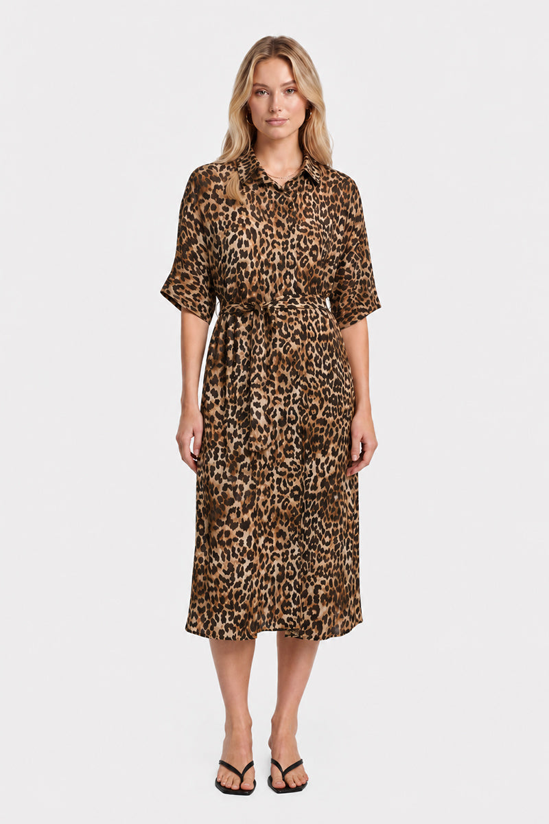 Eine Frau steht mit dem Blick nach vorne und trägt ein knielanges, locker sitzendes Kleid der Marke „Princess Goes Hollywood“ mit Leopardenmuster, kurzen Ärmeln und einem Kragen. Sie hat helles, welliges Haar und trägt schwarze Sandalen mit offener Zehenpartie. Der Hintergrund ist schlicht weiß.