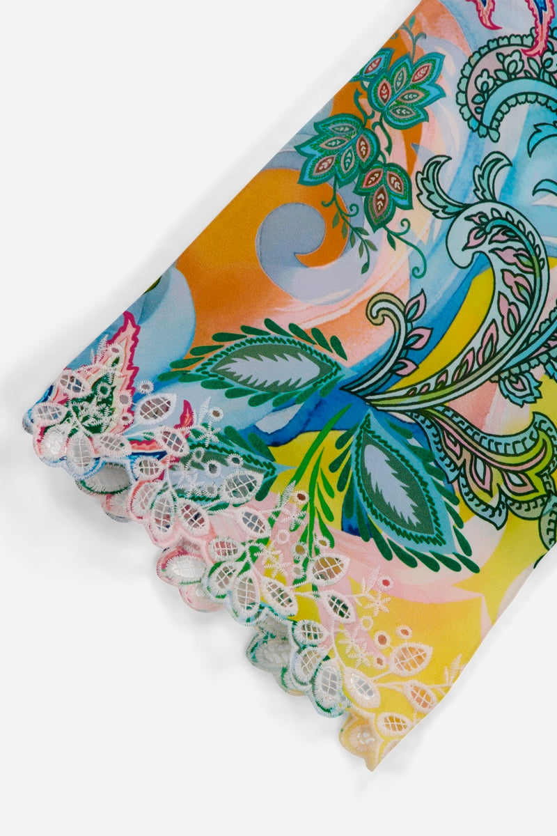 Eine Nahaufnahme eines Princess Goes Hollywood-Stoffärmels mit einem bunten Paisley- und Blumenmuster in Grün, Blau, Orange und Rosa. Der Seidenbluse-Ärmel endet mit einer zarten Spitzenborte und weiß-pastellfarbenen Stickerei-Blattformen.
