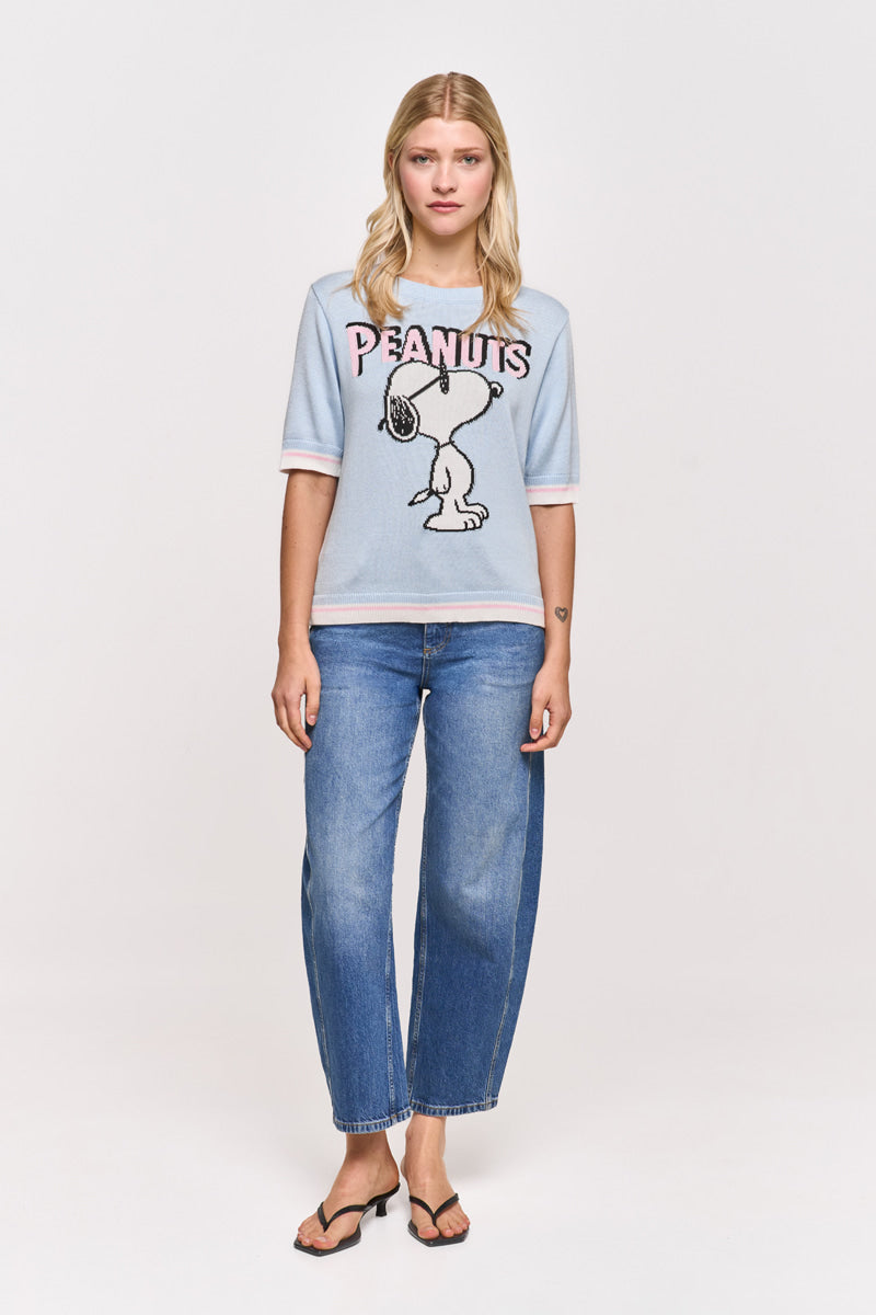 Eine Frau mit blonden Haaren trägt einen hellblauen kurzärmeligen Princess Goes Hollywood Peanuts Pullover aus Baumwollmix mit Snoopy-Motiv, gepaart mit blauen Jeans und schwarzen Sandalen. Sie steht mit dem Gesicht nach vorne vor einem weißen Hintergrund.