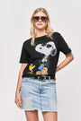 Eine blonde Frau mit Sonnenbrille posiert mit einer Hand an der Hüfte, trägt ein schwarzes Princess Goes Hollywood Snoopy Baumwolle T-Shirt mit Strasssteinen und einen hellblauen Jeansrock vor einem schlichten weißen Hintergrund.