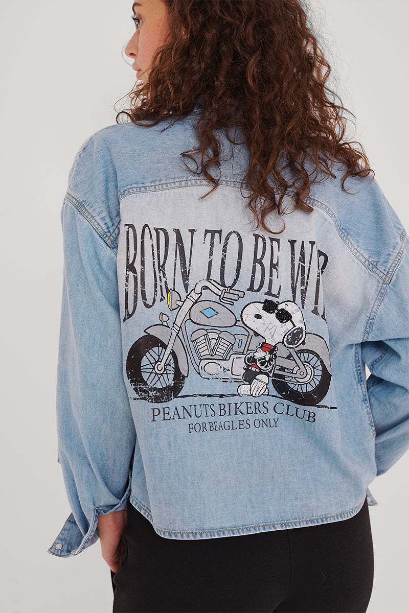 Eine Person mit lockigem braunem Haar, von hinten gesehen, trägt ein hellblaues Princess Goes Hollywood Jeanshemd mit einem Peanuts-Snoopy-Motorradaufdruck. "BORN TO BE WILD" steht über "PEANUTS BIKERS CLUB FOR BEAGLES ONLY".