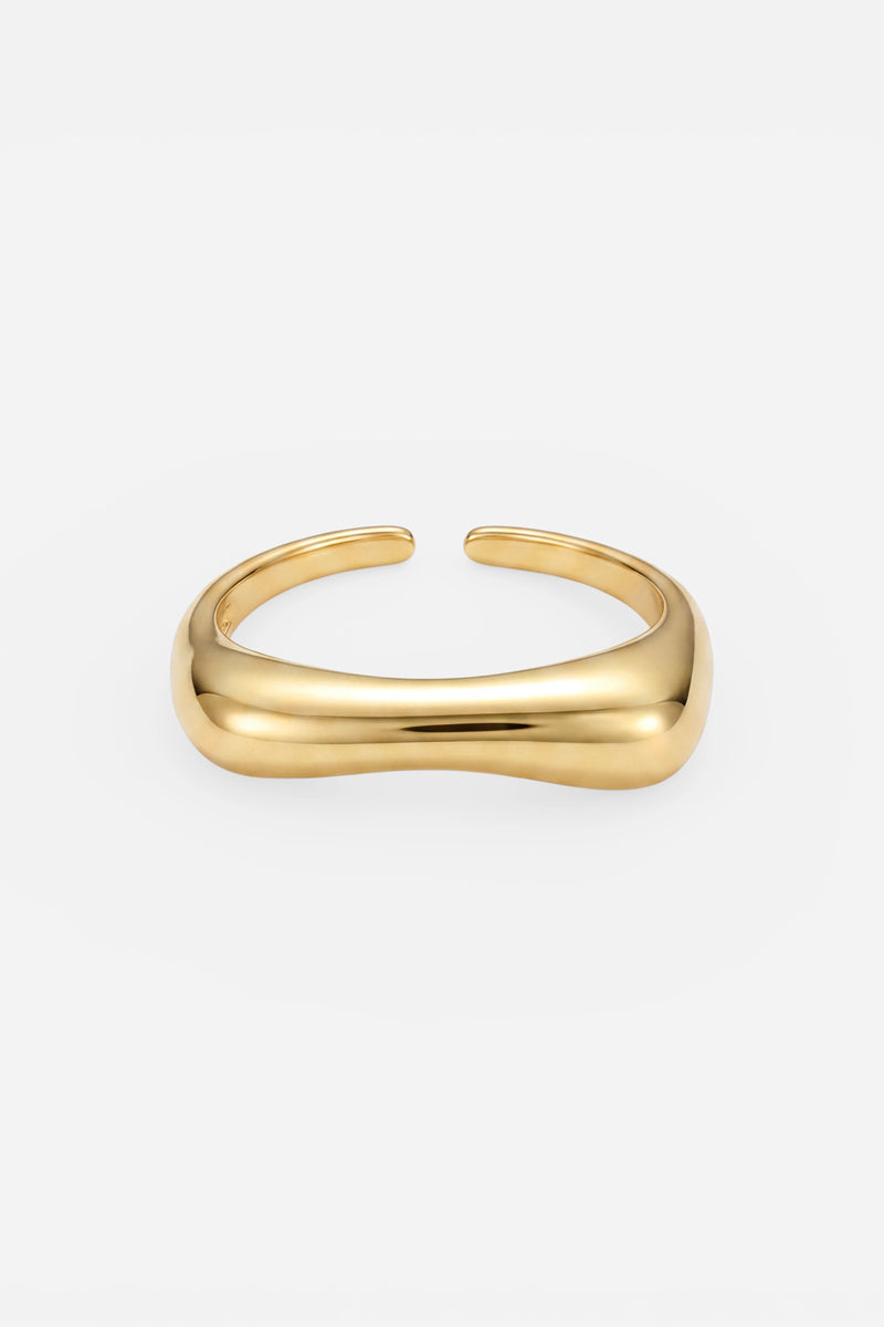 Ein schlichtes, poliertes Goldarmband von Princess Goes Hollywood besticht durch ein glattes, leicht geschwungenes Design mit einer 18-Karat-Vergoldung. Das offene Armband hat abgerundete Kanten und eine glänzende Oberfläche und wird vor einem schlichten weißen Hintergrund präsentiert, was ihm einen modernen und minimalistischen Look verleiht.